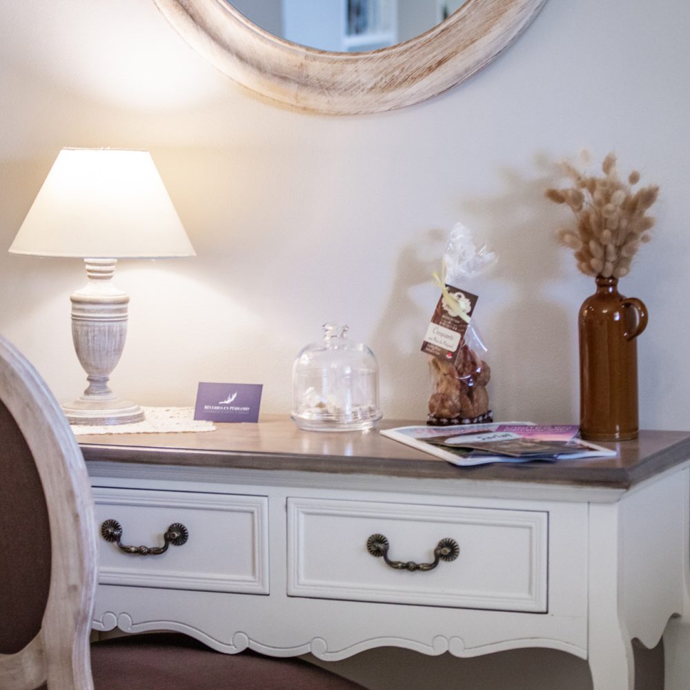 Coiffeuse blanche avec miroir, lampe et fleurs séchées dans la Chambre Bergerac