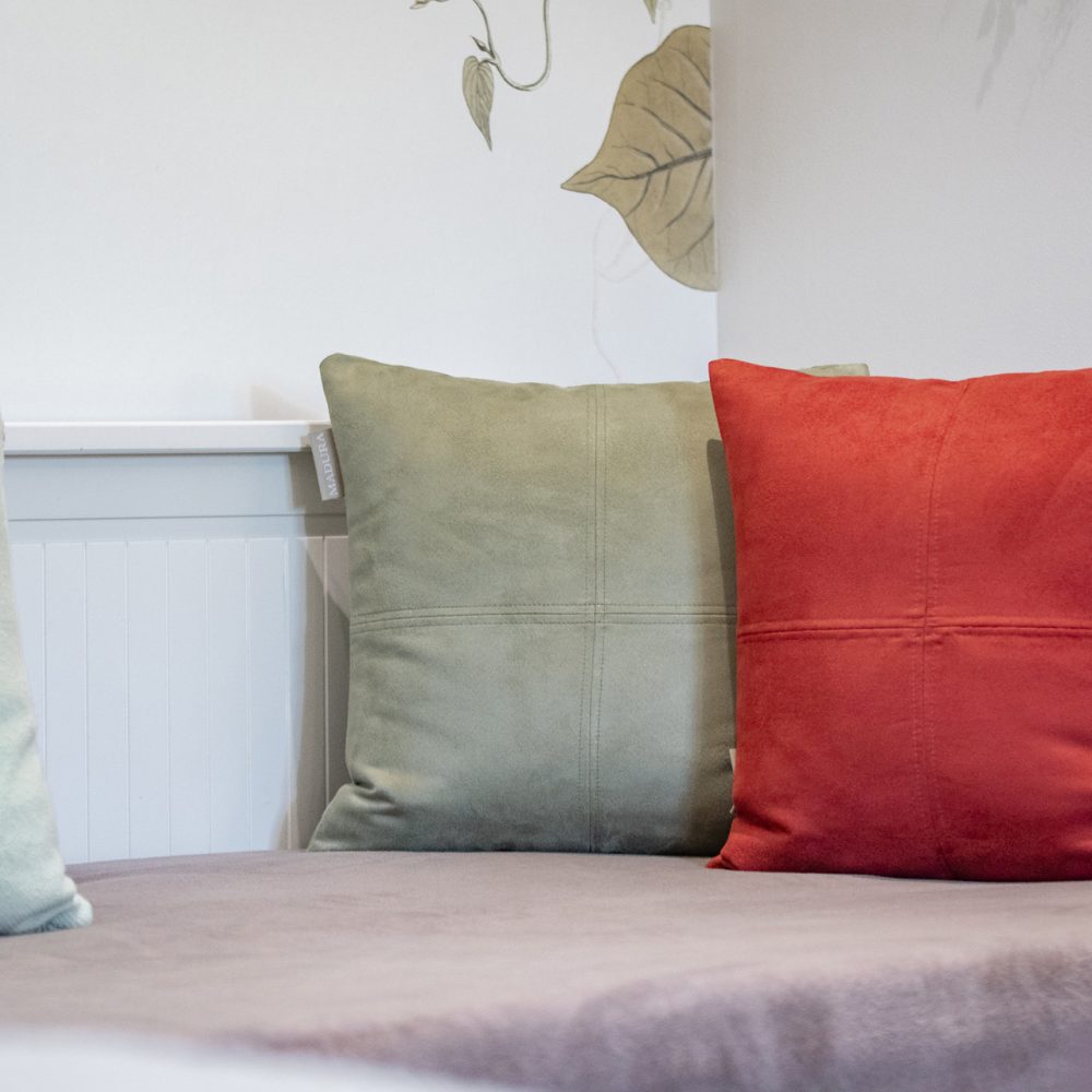 Coussins rouge et vert sur le lit au papier peint doré de la Chambre Bergerac