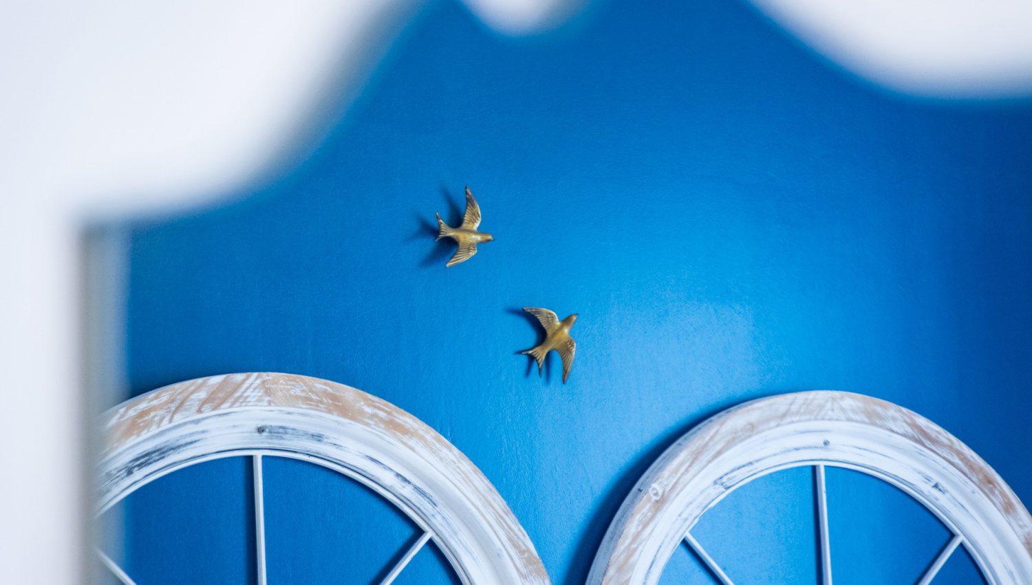 Tête de lit en arches blanches ornée d'oiseaux dorés sur mur bleu, Chambre Brantôme