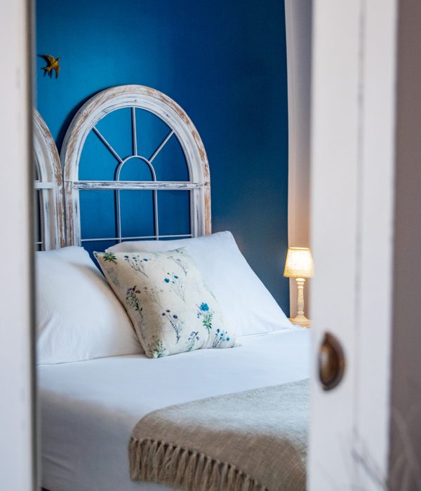 Tête de lit bleue, coussin brodé et lampe de chevet dans la Chambre Brantôme