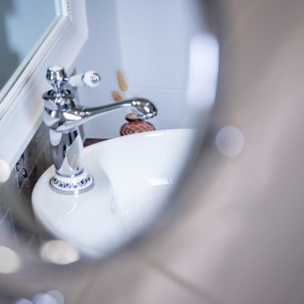 Mitigeur et miroir rond au-dessus de la vasque de la Chambre Brantôme