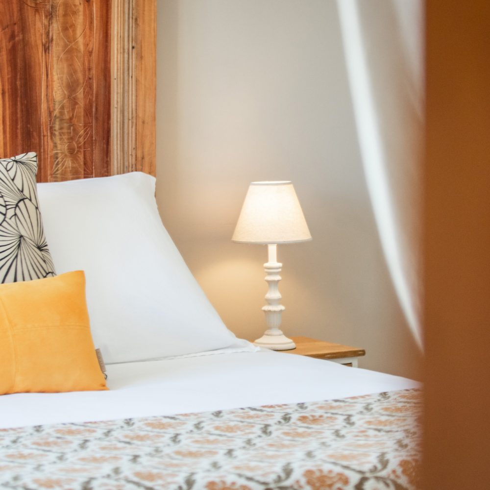 Lit avec coussin moutarde et lampe de chevet dans la Chambre Sarlat