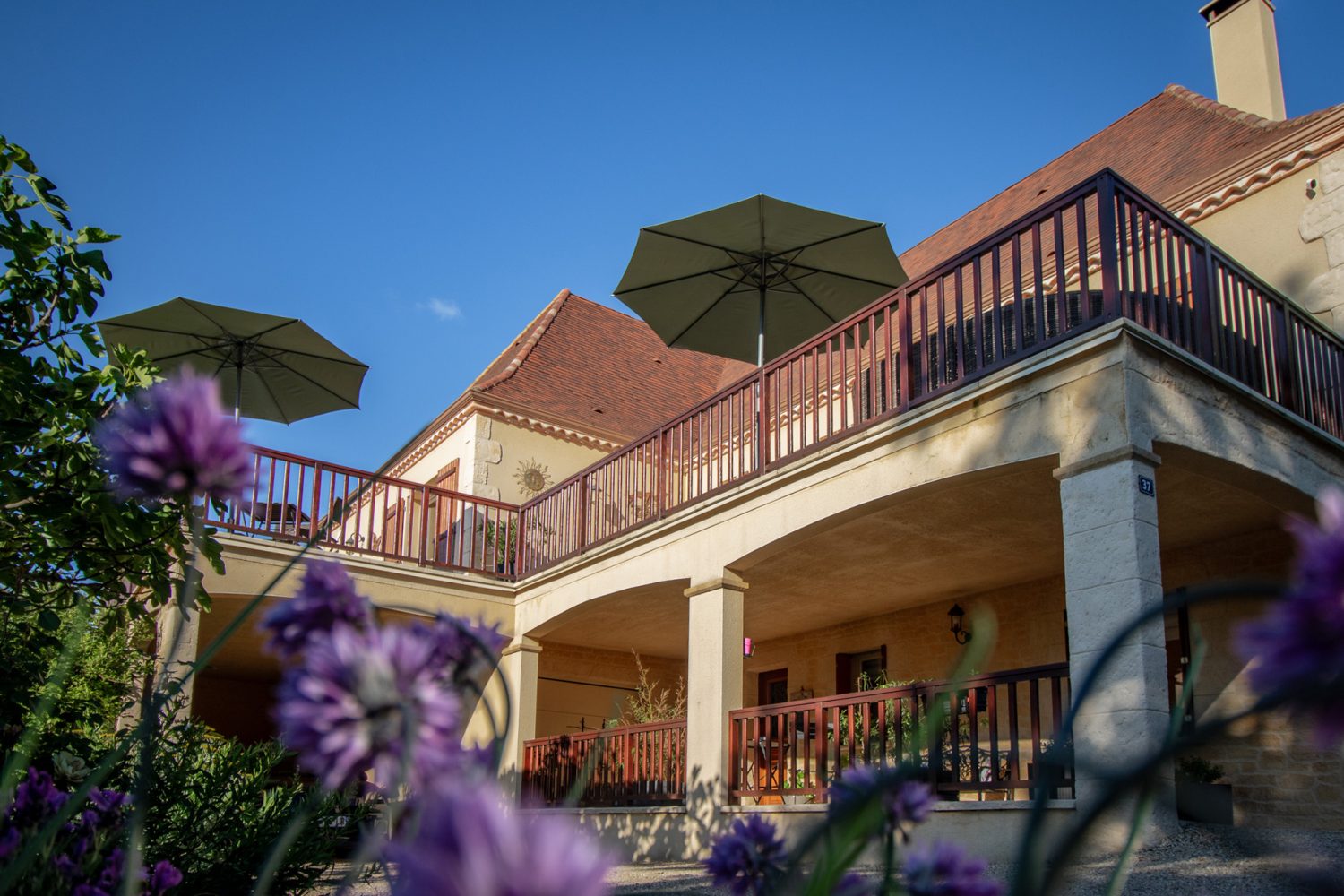 Terrasse et parasols de la maison d’hôtes dans un jardin fleuri à Sarlat