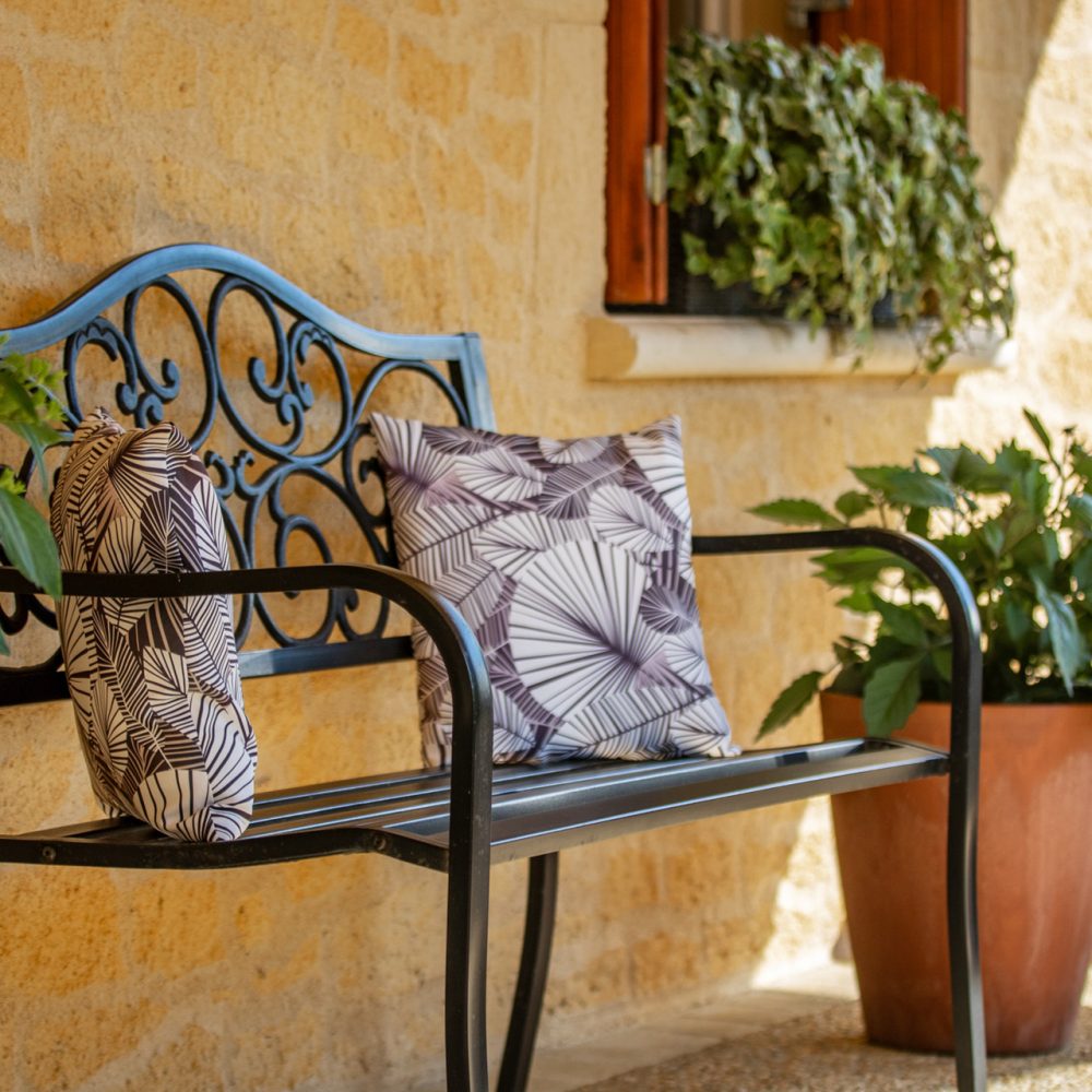 Banc en fer et plantes contre un mur en pierre, terrasse d’une maison d’hôtes à Sarlat