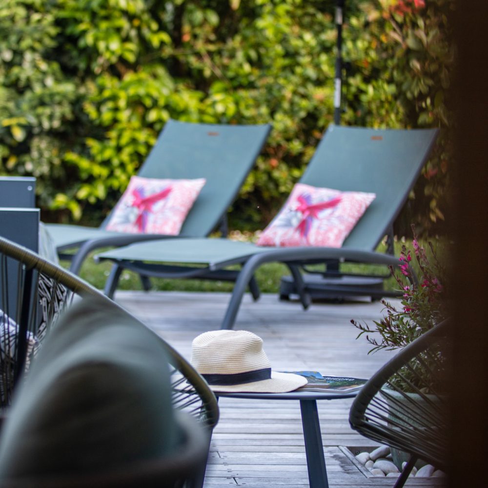 Transats à coussins roses sur la terrasse face au jardin, maison d’hôtes à Sarlat
