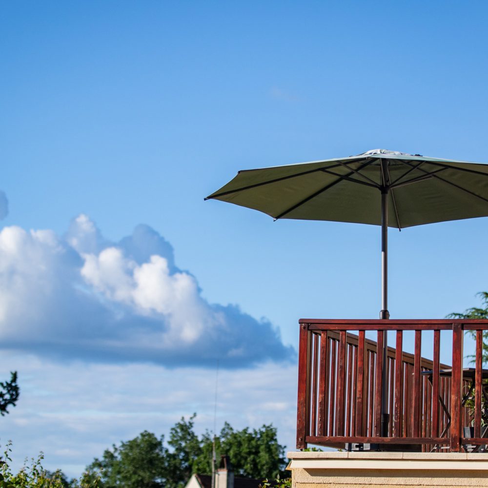 Terrasse et parasol sous un ciel d’été, maison d’hôtes de charme à Sarlat en Périgord