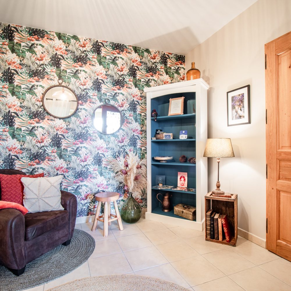 Coin salon avec fauteuil en cuir et mur fleuri, maison d’hôtes de charme près de Sarlat