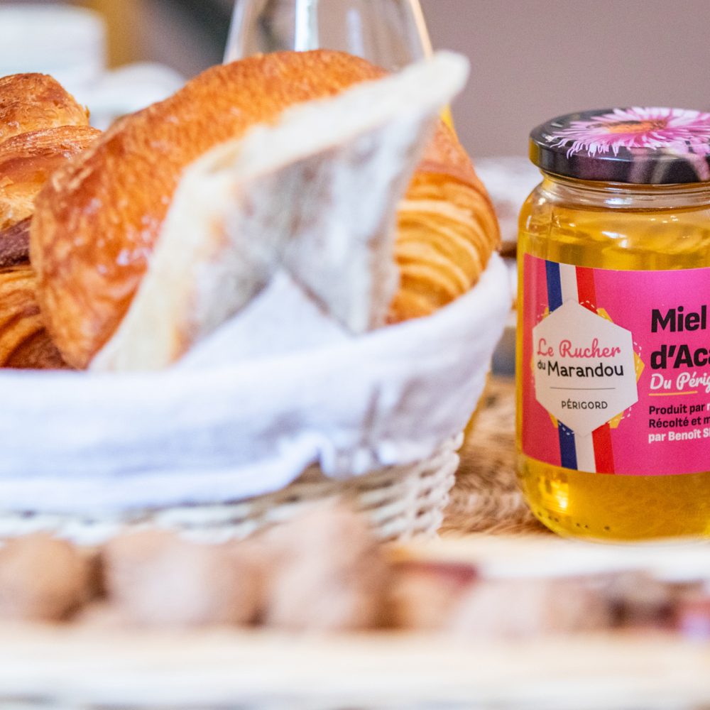 Panier de viennoiseries et pot de miel au petit-déjeuner en Périgord noir
